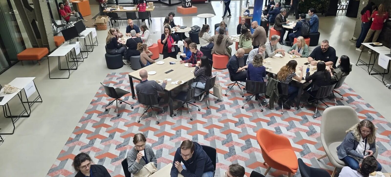 Conference attendees eating and talking at tables in the MindLabs atrium, seen from above